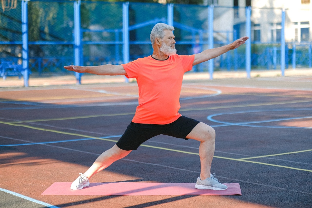 white haired man demonstrating stretching exercises for seniors