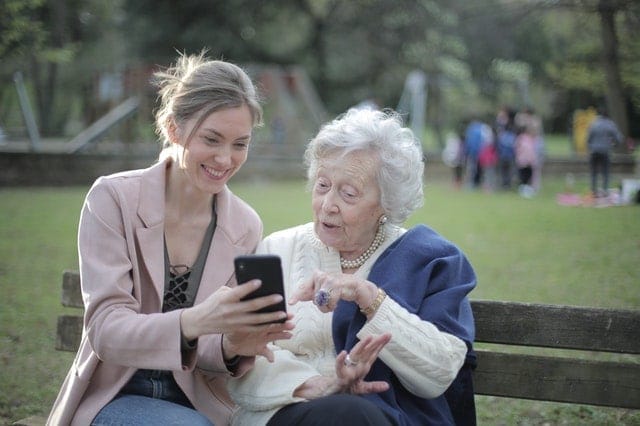 Caregiver assisting elderly lady with smart phone. 