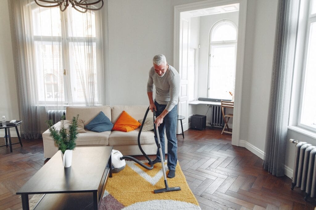 Man performing vacuuming as instrumental activity of daily living. 