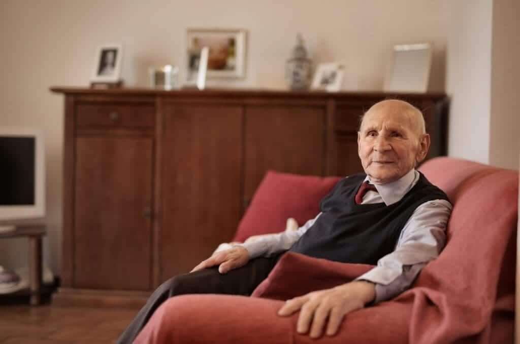 Man sitting on couch discussing caring for the aging.